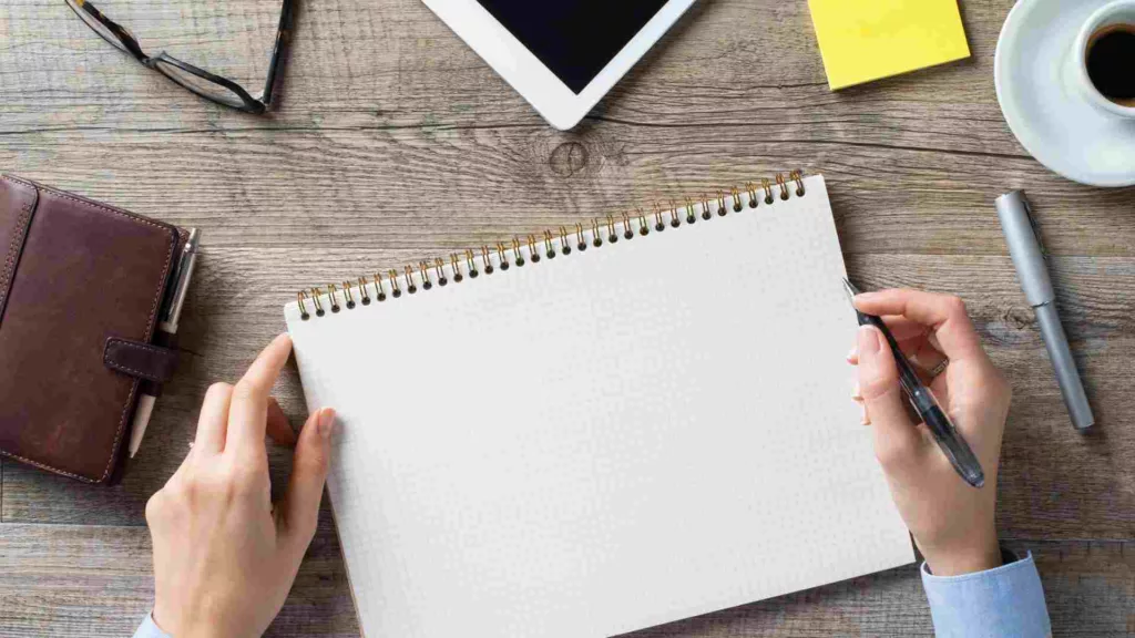 blank page in notebook with person thinking what to write