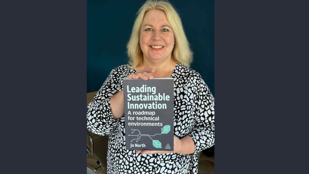 Dr. Jo North holding a copy of her book, Leading Sustainable Innovation, in her hands, facing the front