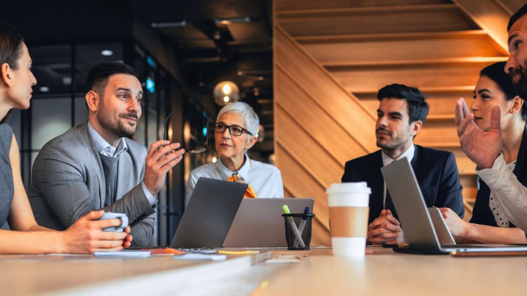 Business people discussing and smiling, seated around a meeting table